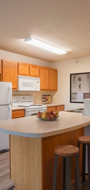 a kitchen with white appliances and wooden cabinets and a island with three stools
