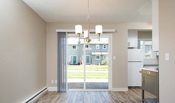 an empty living room with a large window and a kitchen
