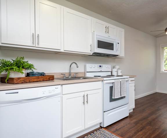 A white kitchen with wood floors and a window.