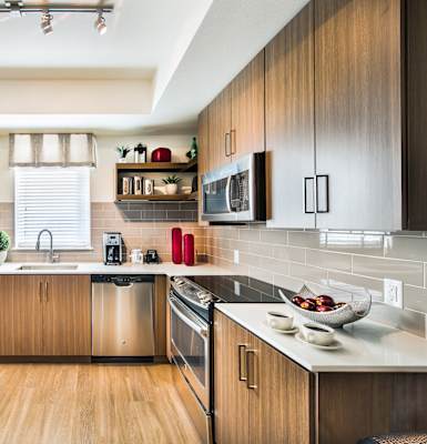 A modern kitchen with wooden cabinets and stainless steel appliances. at 8000 Uptown Apartments, Broomfield, CO, 80021