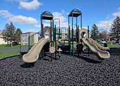 Thumbnail 33 of 38 - A playground with a green slide and a brown tower.