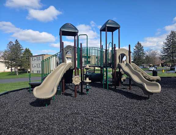 A playground with a green slide and a brown tower.