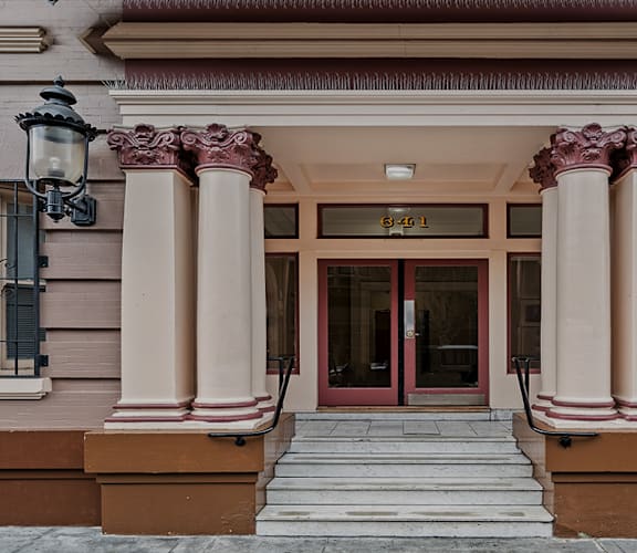 the front of a building with columns and a red door