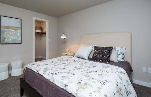 A bedroom with a bed, nightstand, and two stools.