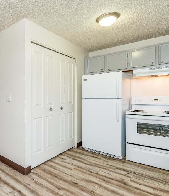 A kitchen with white appliances and cabinets with a sliding glass door leading to a backyard.