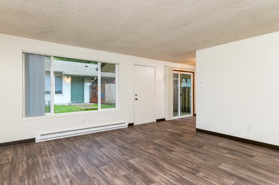 Pinewood Terrace Apartments | Living Room with large window, front door and view of patio sliding door in dining room.