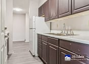 Thumbnail 2 of 7 - A kitchen with a white fridge and brown cabinets.