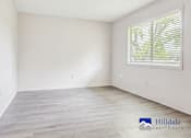 Thumbnail 1 of 7 - A spacious room with a window and wooden flooring.