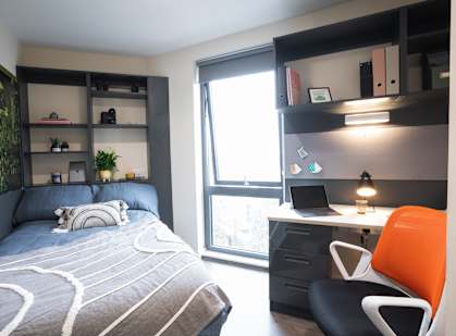 a bedroom with a bed and a desk with a laptop