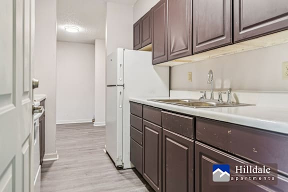 A kitchen with a white fridge and brown cabinets.
