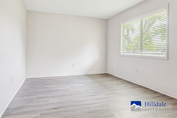 A spacious room with a window and wooden flooring.