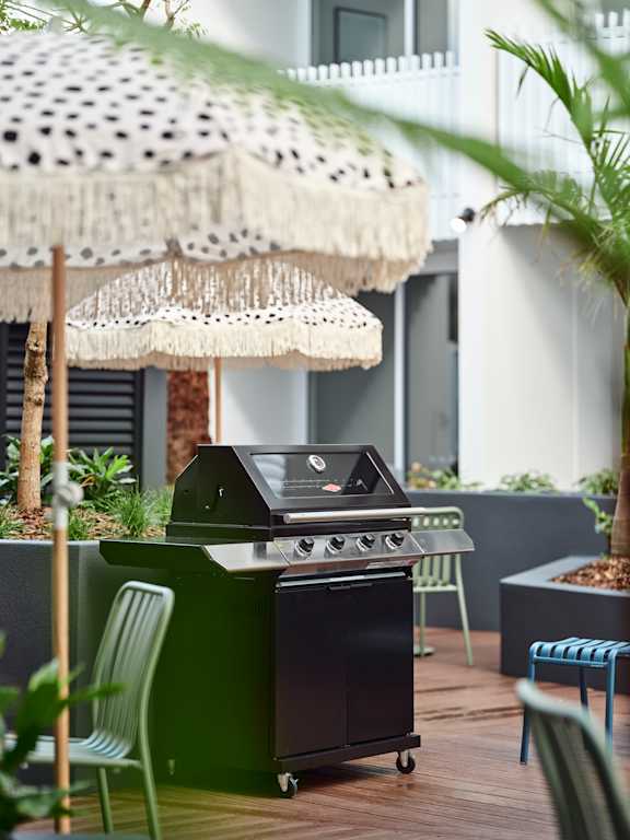 a barbecue grill on a patio with chairs and umbrellas