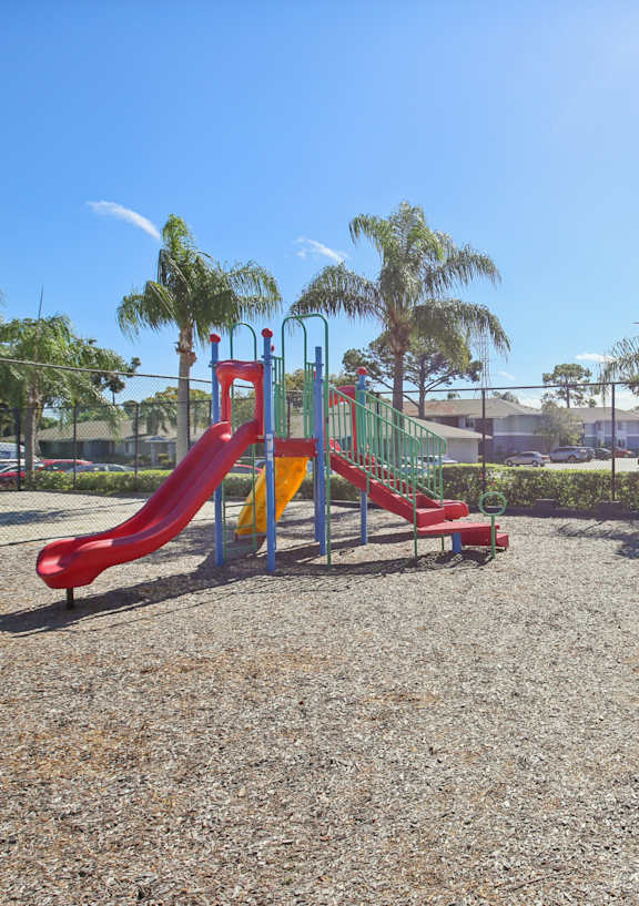 A playground with a red slide and green bench.
