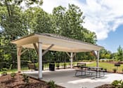 Thumbnail 55 of 64 - A pavilion with a white roof and a picnic table is surrounded by a mulched garden bed.