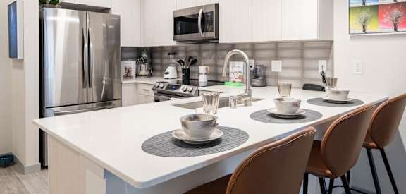 A modern kitchen with a white table and chairs.