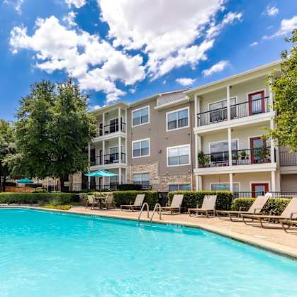 A swimming pool in front of a multi-story apartment building.