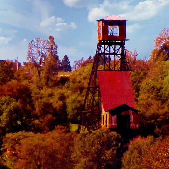 A tall red and brown tower stands in a field of green grass.