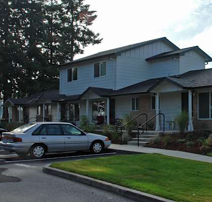 A grey house with a car parked in front.