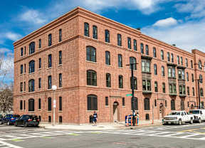 A red brick building with a white truck parked in front.