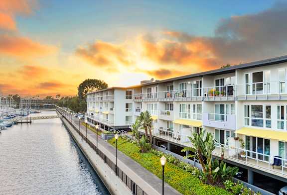 A row of white buildings with balconies line a waterway.