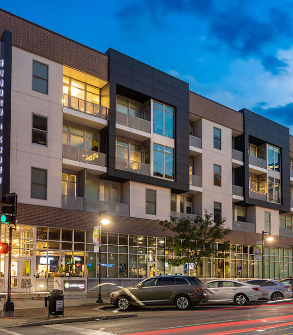 A modern apartment building with cars parked in front.
