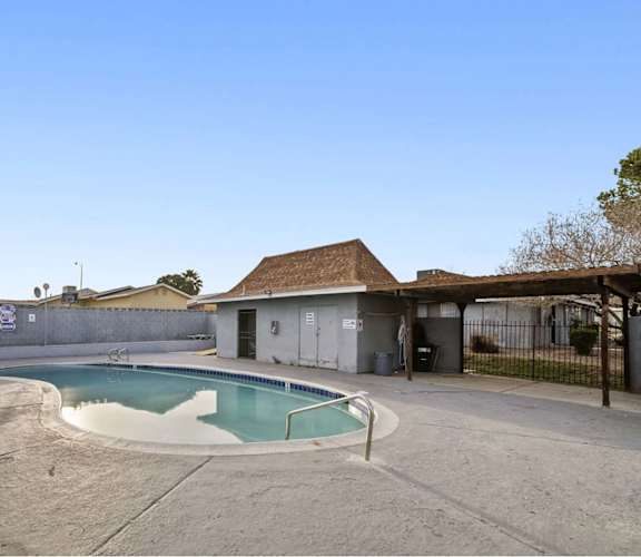 A small pool in a backyard with a building in the background.