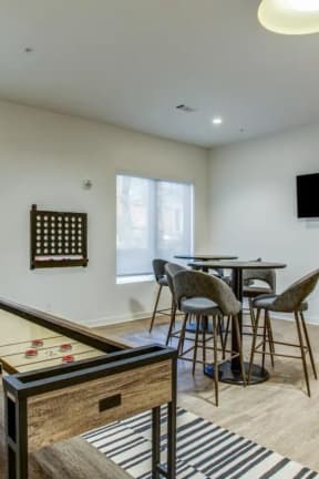 a game room with a pool table and a bar with chairs and a television