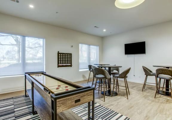 a game room with a pool table and a bar with chairs and a television