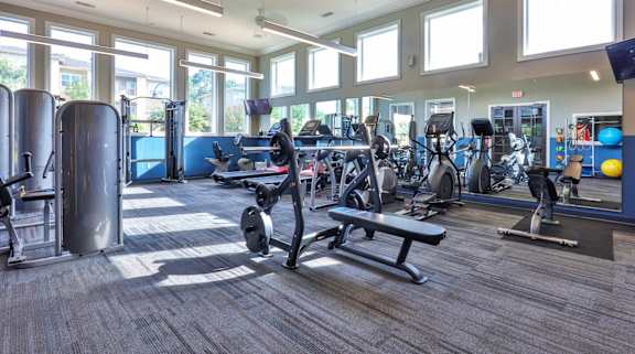 a gym with cardio equipment and windows in a building