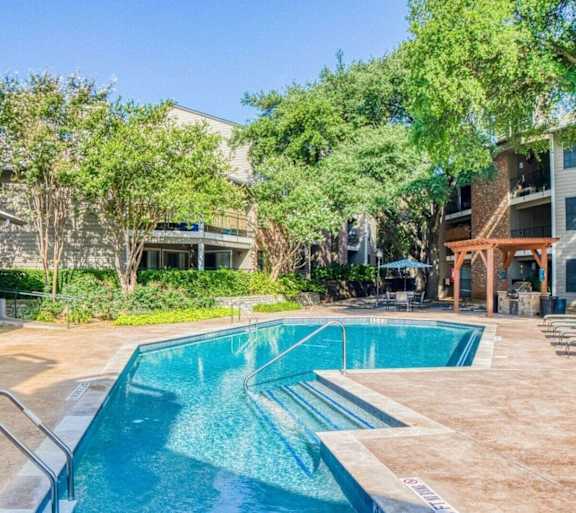 view of the pool from the rightside with trees and building at Hillside Creek in Austin, TX
