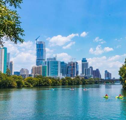 people kayaking on a river with the city skyline in the background