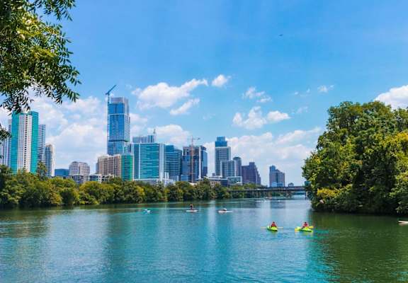 people kayaking on a river with the city skyline in the background