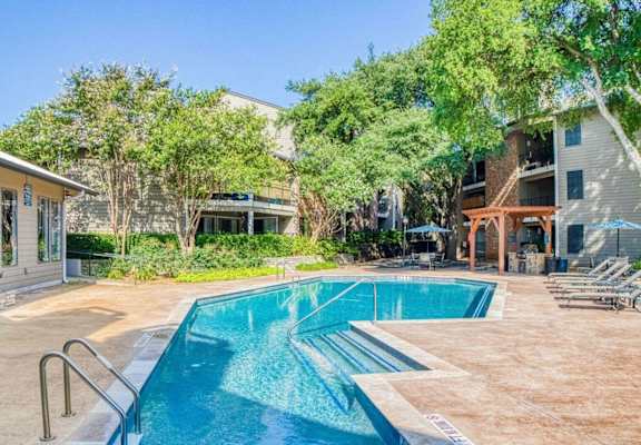 view of the pool from the rightside with trees and building at Hillside Creek in Austin, TX