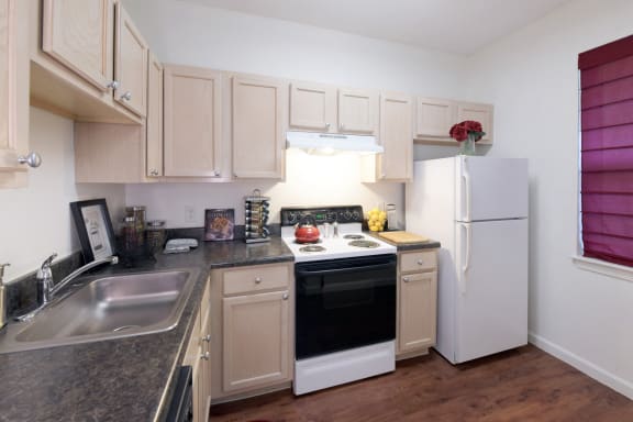 kitchen with stovetop, oven, dishwasher, and granite countertops at Cumberland Crossing in Rhode Island 02864