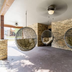 a living room with three hanging hammock chairs and a brick wall