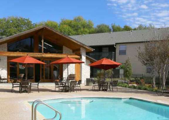 A large house with a pool and patio furniture.