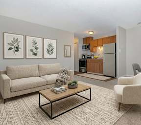A living room with a beige couch, a coffee table, and a dining table with chairs.