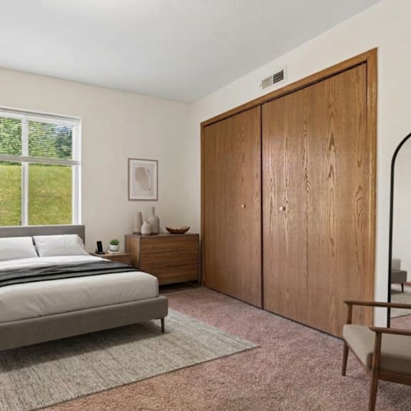 A bedroom with a large bed, a nightstand with a lamp, a chair, and a wardrobe.