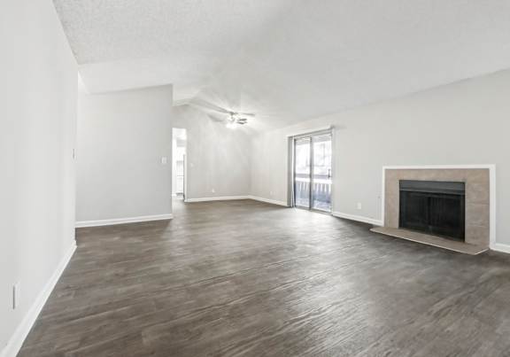 A spacious living room with a fireplace and sliding glass doors in C2b floor plan at Riverwood Crossing apartments in Roswell, GA..