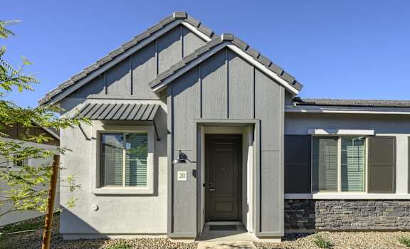 a gray house with a black door and a blue sky at Village of Chandler, Arizona, 85249