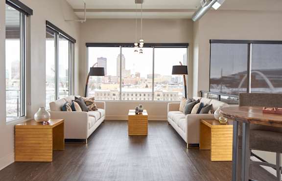A modern living room with white furniture and a view of the city.