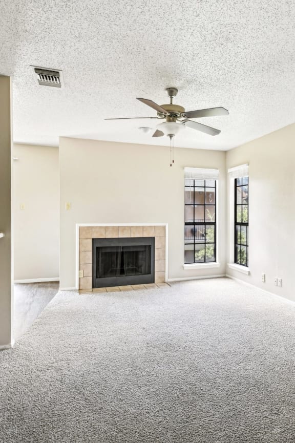Living room with fireplace and carpet floor at Bandera Crossing apartments in San Antonio, TX