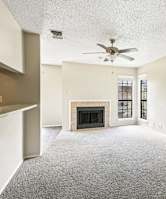 Living room with fireplace and carpet floor at Bandera Crossing apartments in San Antonio, TX