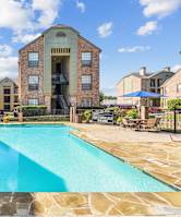 Swimming pool surrounded by apartment buildings with lounge chairs at Bandera Crossing apartments in San Antonio, TX