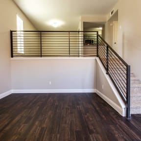 the upstairs living room of a new home with a staircase and wood flooring