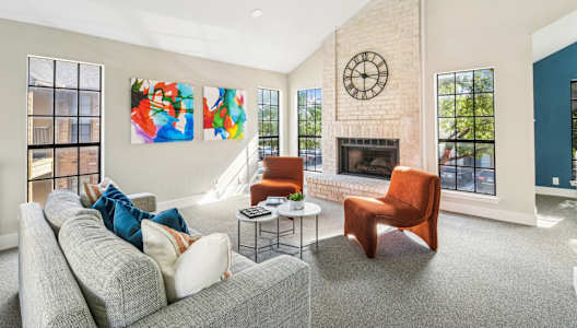 Cozy lounge space in clubhouse with fireplace, couch and orange plush seats at Bandera Crossing apartments in San Antonio, TX