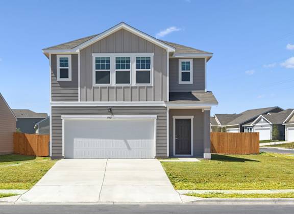 a house with a white garage door in front of a green lawn