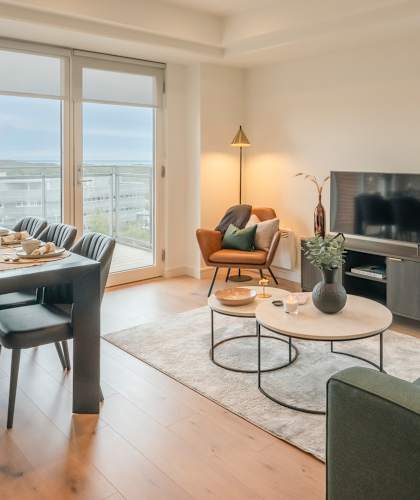 A modern living room with a dining table and a green sofa.