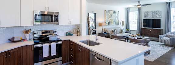 a kitchen with white cabinets and a large white island with a stainless steel sink and dishwasher at Canopy at Ginter Park Apartments, Richmond, VA, 23227