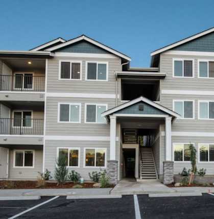 A large apartment building with a parking lot in front.